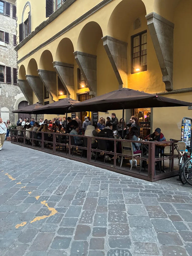 La facciata di GustaPizza sotto il loggiato giallo in Via Maggio, Oltrarno