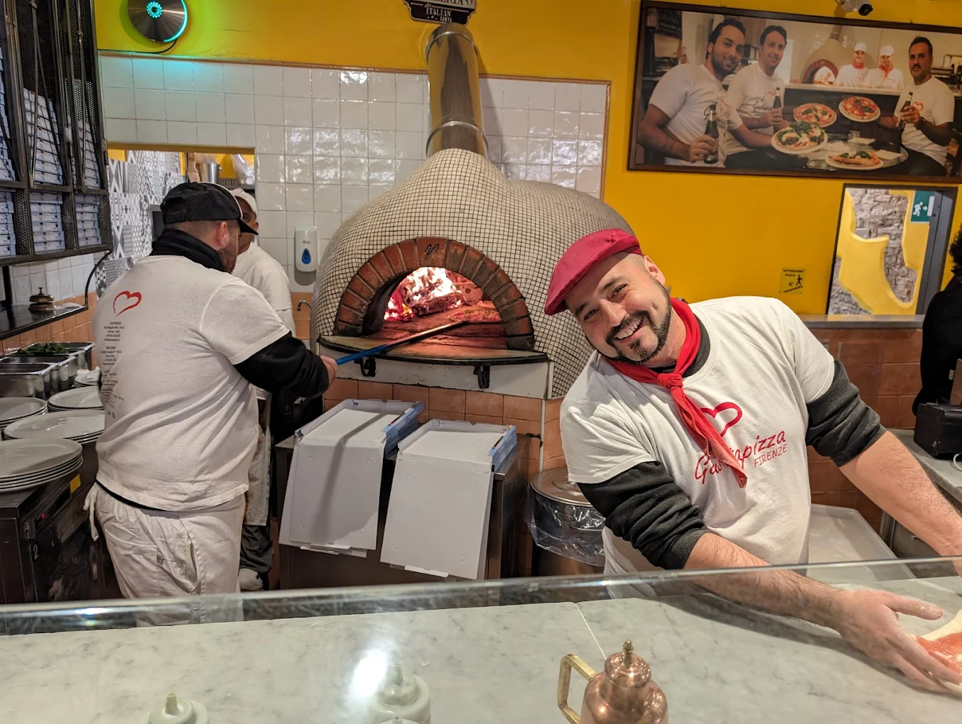 Pizzaiolo di GustaPizza al forno a legna, con la maglia dal logo a cuore