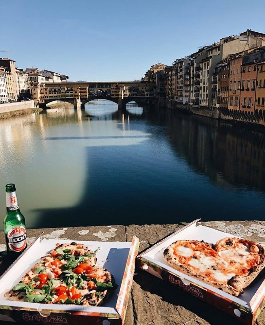 Pizza Margherita a forma di cuore nel cartone da asporto sul lungarno, con Ponte Vecchio sullo sfondo